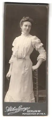 Fotografie Atelier George, Berlin, Potsdamer Str. 116a, Portrait Dame im weissen Kleid mit Halskette schaut keck