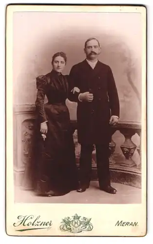 Fotografie J. Holzner, Meran, Portrait eines elegant gekleideten Paares