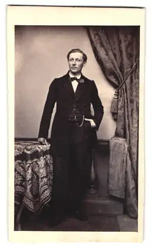 Fotografie Josef Lorenz, Ort unbekannt, Portrait Herr im adretten Anzug mit Fliege steht lässig am Tisch
