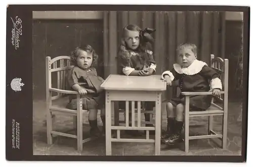 Fotografie H. Simson, Rosenheim, Münchnerstrasse 6, drei Geschwister im feinen Zwirn am Kindertisch