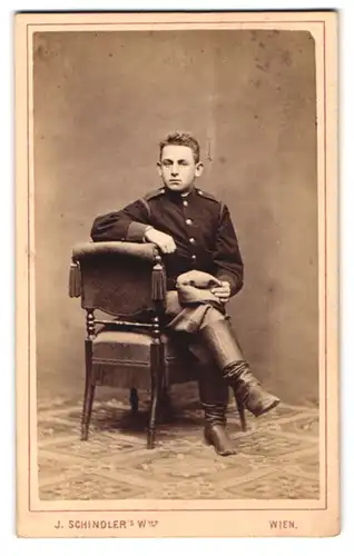 Fotografie H. Schindler, Wien, Neubaugasse 31, Portrait junger Soldat in Uniform auf einem Stuhl sitzend