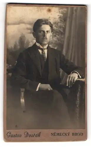 Fotografie Gustav Dvorak, Nemecky Brod, Portrait Mann im Anzug mit Schlips vor einer Studiokulisse