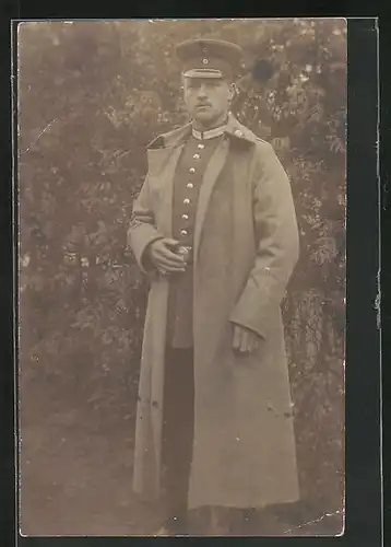 AK Uniformfoto, junger Soldat im Mantel im Garten