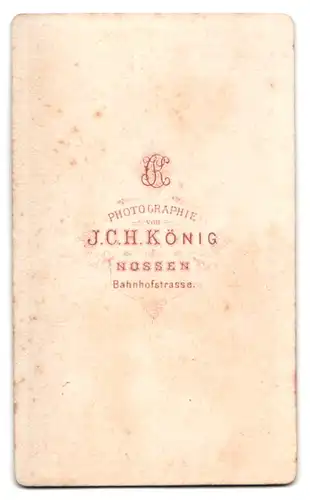 Fotografie J. C. H. König, Nossen, Bahnhofstr., Portrait frecher Bube im Anzug am Tisch stehend