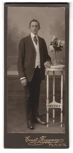 Fotografie Ernst Freygang, Penig i. S., Portrait junger charmanter Mann im Anzug an einem Tisch stehend