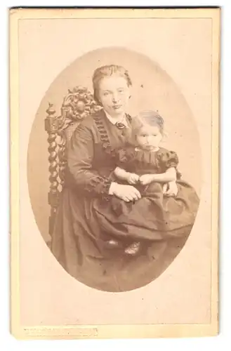 Fotografie F. H. Bödeker, Hildesheim, Portrait stolze hübsche Mutter mit süsser Tochter auf dem Schoss