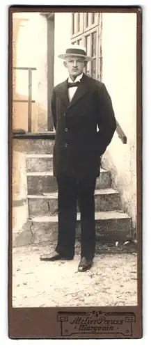 Fotografie Atelier Preuss, Margonin, Portrait charmanter junger Mann mit Hut im Anzug vor einem Haus stehend