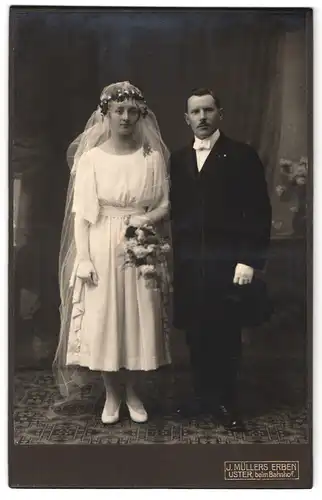 Fotografie J. Müllers Eben, Uster, Portrait junges Paar in Hochzeitskleidung mit Schleier und Blumenstrauss