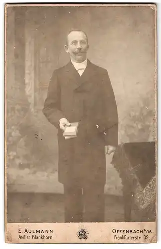 Fotografie E. Aulmann, Offenbach a. M., Frankfruterstrasse 39, Portrait eleganter Herr mit Schnauzbart und Buch