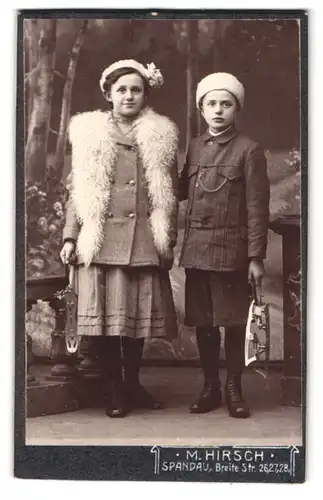 Fotografie M. Hirsch, Spandau, Breite Str. 29-28, Portrait zwei Kinder mit Schlittschuhen vor einer Studiokulisse