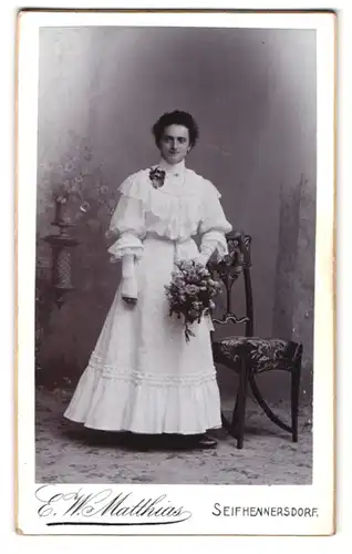 Fotografie E. W. Matthias, Seifhennersdorf, Portrait junge Frau im weissen Kleid mit Blumenstrauss, Kommunion