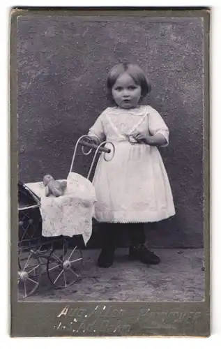 Fotografie Aug. Allen, Hannover, Portrait kleines Mädchen im Kleid mit Puppenwagen und Puppe