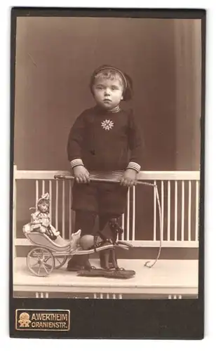 Fotografie A. Wertheim, Berlin, Oranienstr., Portrait Knabe im Wollanzug mit Puppenwagen und Puppe