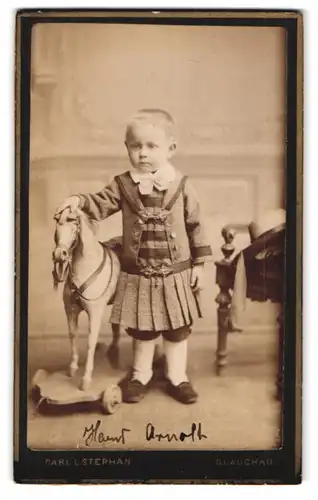 Fotografie Carl L. Stephan, Glauchau, Hoffnung 47, Portrait Knabe Hans Arnold im Kleid mit Schaukelpferd