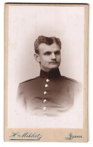 Fotografie H. Mehlert, Itzehoe, Breitestr. 25, Portrait Soldat in Uniform mit Zwirbelbart und Locken
