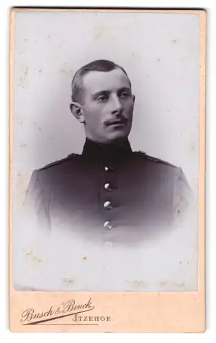 Fotografie Busch & Beuck, Itzehoe, Portrait Soldat in hoch geschlossener Uniform mit kleinem Zwirbelbart