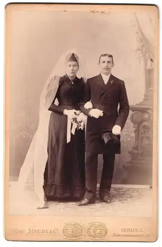 Fotografie Hugo Strube & Co., Berlin, Prinzessinnenstr. 16, Portrait Ehepaar im schwarzen Kleid und Anzug mit Zylinder