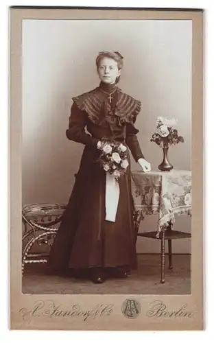 Fotografie A. Jandorf & Co., Berlin-SW, Bellealliancestrasse 1-2, Portrait junge Dame im Kleid mit Kreuzkette und Blumen
