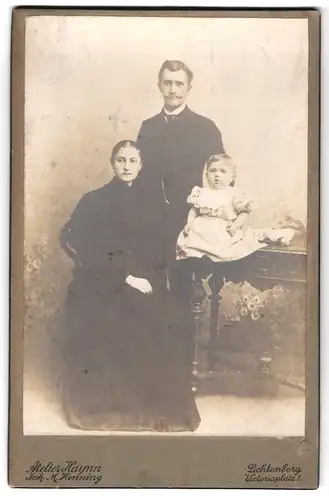 Fotografie M. Henning, Berlin-Lichtenberg, Victoriaplatz 1, Portrait elegantes Paar mit einem Kleinkind