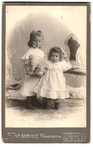 Fotografie Samson & Co., Frankfurt a. M., Kaiserstrasse 1, Portrait zwei kleine Mädchen in weissen Kleidern mit Spieltier