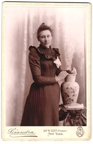 Fotografie Sciandra, New York, N. Y., 118, W. 125th Street, Portrait junge Dame im Kleid mit einer Vase