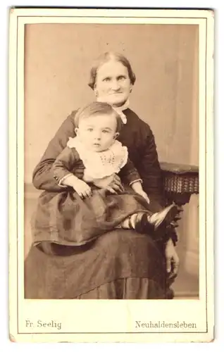 Fotografie Fr. Seelig, Neuhaldensleben, Langestrasse 50, Portrait ältere Dame im Kleid mit Kleinkind auf dem Schoss
