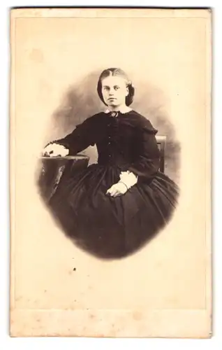 Fotografie unbekannter Fotograf und Ort, Portrait junge Frau im schwarzen reifrock Kleid mit Brosche