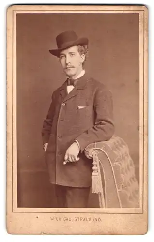 Fotografie Wilh. Gau, Stralsund, Böttcher-Str. 9, Portrait Herr im Anzug mit Stetson und Fliege, Moustache