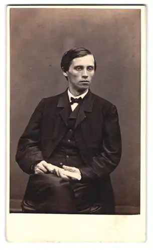 Fotografie unbekannter Fotograf und Ort, Portrait junger Mann im dunklen Anzug mit Fliege und Schriftstück in der Hand