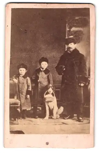 Fotografie F. M. Depaul, Riedlingen, Portrait Vater mit zwei Kindern und Hund in Wintermänteln und Mützen