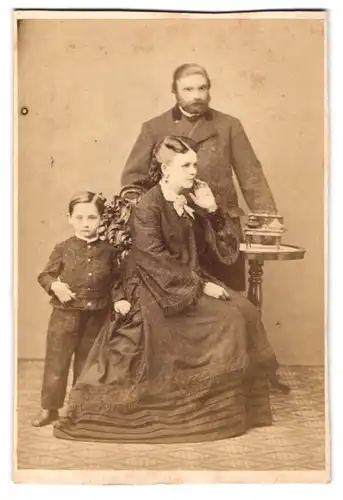 Fotografie unbekannter Fotograf und Ort, Portrait Mutter und Vater mit Sohn im Anzug und Biedermeierkleid im Atelier