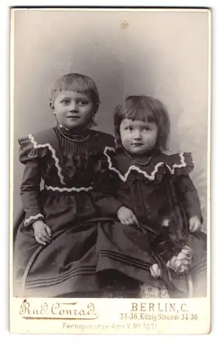 Fotografie Rud. Conrad, Berlin, Königstrsse 34-36, Portrait zwei kleine Mädchen in modischen Kleidern
