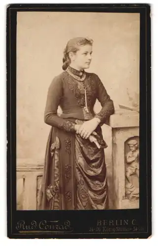 Fotografie Rud. Conrad, Berlin, Königstrasse 34-36, Portrait hübsch gekleidete Dame mit einem Buch