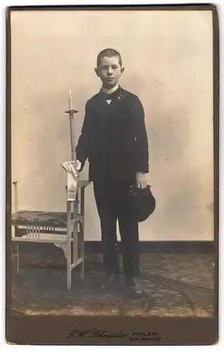 Fotografie P. W. Schneider, Aalen, beim Bahnhof, Portrait Knabe Hugo Heffner im Anzug mit langer Kerze, Kommunion