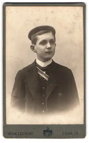 Fotografie Wilh. Leukert, Leipa i. B., Portrait junger Student im Anzug mit Tellermütze und Couleur