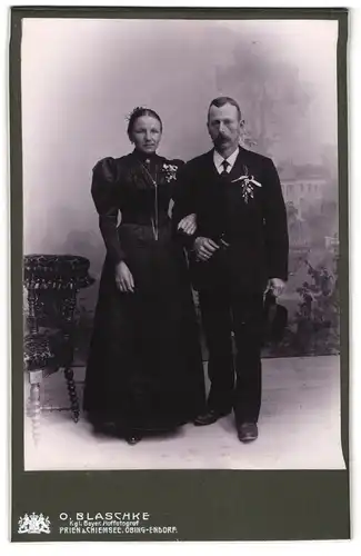 Fotografie O. Blaschke, Prien a. Chiemsee, Portrait Eheleute im schwarzen Kleid und Anzug mit Ansteckblume
