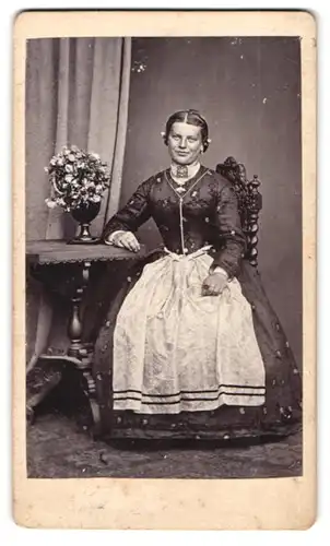 Fotografie J. Liesack, Rosenheim, Heiligengeistgasse 225, Portrait Dame im Trachtenkleid sitzend am Tisch