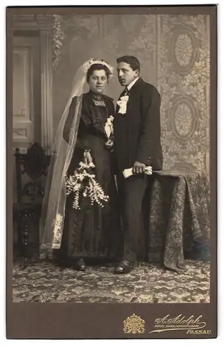 Fotografie A. Adolph, Passau, Portrait junges Paar in Hochzeitskleidung mit Schleier und Blumenstrauss