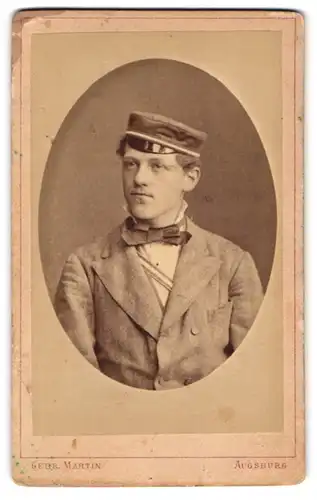 Fotografie Gebr. Martin, Augsburg, Portrait junger Student im Anzug mit Biedermeiermütze und Couleur