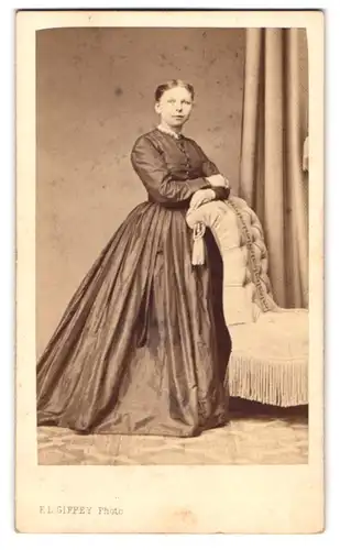 Fotografie F. L. Giffey, Hamburg, Neuerwall 82, Portrait junge Frau im seidenen Kleid lehnt an einem Sessel