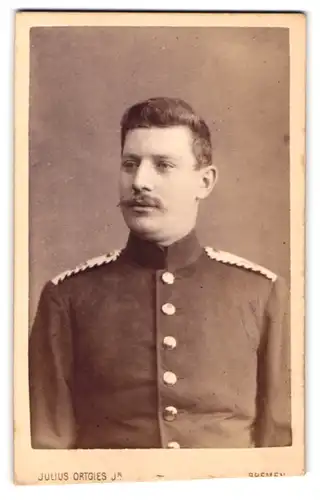 Fotografie Julius Ortgies, Bremen, am Wall 116, Portrait stattlicher junger Mann in interessanter Uniform