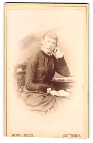 Fotografie Bernh. Petri, Göttingen, Weenderstr. 80, Portrait blonde hübsche Frau im Kleid am Tisch sitzend