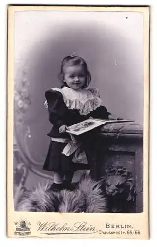 Fotografie Wilhelm Stein, Berlin, Chausseestr. 65 /66, Portrait lächelndes Mädchen im Kleid mit Rüschekragen liest Buch