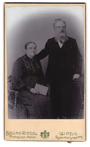 Fotografie Bruno Riedel, Leipzig, Rosentalgasse 9, Portrait älteres Paar in hübscher Kleidung mit Buch