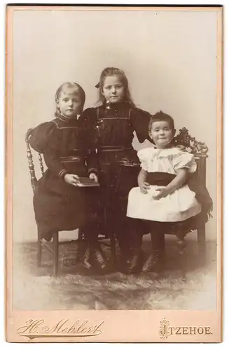 Fotografie H. Mehlert, Itzehoe, Portrait drei Mädchen in hübschen Kleidern mit Buch