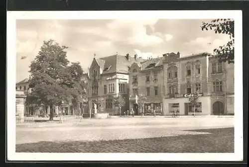 AK Unicov, Strassenpartie mit Geschäften und Brunnen