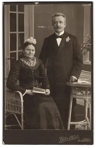 Fotografie Victor Keil, Jena, Inselplatz 3, Portrait Eheleute im schwarzen Kleid und Anzug mit Blumenschmuck