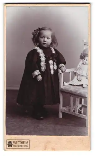 Fotografie Wertheim, Berlin, Rosenthalerstr., Portrait kleines Mädchen im Kleid mit Spitzenbesatz und Puppe auf Stuhl