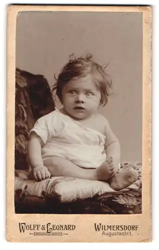 Fotografie Wolff & Leonard, Wilmersdorf, Augustastr. 1, Kleinkind im weissen Leibchen mit zerzausten Haaren