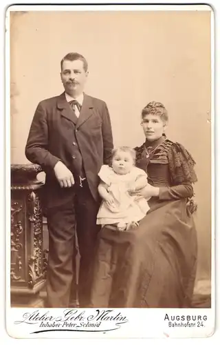 Fotografie Gebr. Martin, Augsburg, Bahnhofstrasse 24, Portrait bürgerliches Paar mit einem Kleinkind